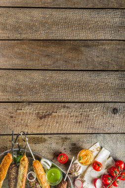 Yaz bbq partisi. Çubukta şiş kebap, kıyma ve tavuk etinden. Lula kebap, geleneksel Kafkas Asya yemeği. Çeşitli soslar, baharatlar ve domateslerle, gri taş arka plan, yukarıdaki boşluğu kopyala