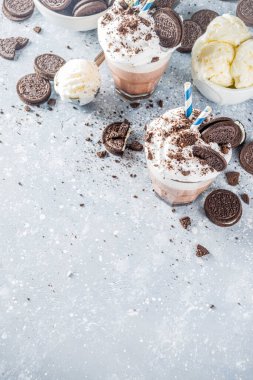 Kahve, sütlü ve kurabiyeli milkshake. Dondurma ve çikolatalı kurabiyeler tatlı latte kokteyli. Kaşık ve vanilyalı dondurmayla birlikte gri beton masada. Boşluğu kopyala