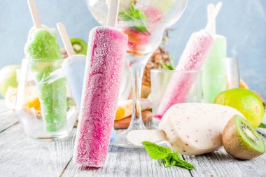 Renkli meyveli dondurma. Çubuklarda sulu dondurma lolipopları, farklı taze tropik meyveler, ahşap arka plan kopyalama alanı