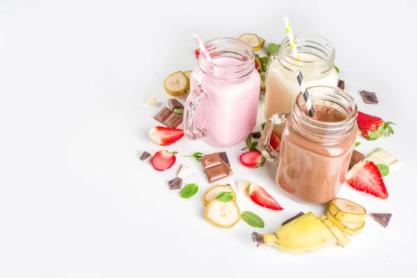 ミルクセーキまたはスムージーと3つのメイソン瓶 夏の健康的な朝食 ランチドリンク 木製の背景にバナナ チョコレート ストロベリーミルクシェーク — ストック写真