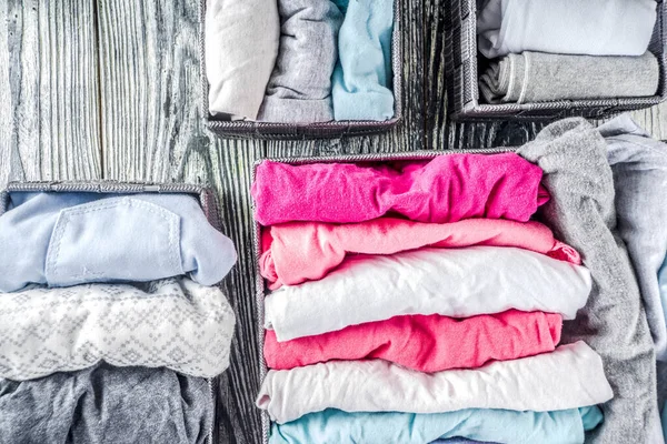 House cleaning concept. Vertical tidying up storage. Marie Kondo tidying method. Neatly folded clothes in the organizer boxes for wardrobe. Wooden background copy space above