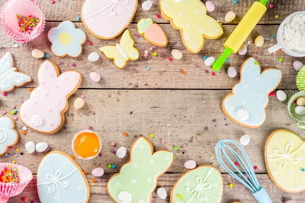 Pastel renkli Paskalya kurabiyeleriyle mutlu paskalya arkaplanları - tavşanlar, yumurtalar, çiçekler, kelebekler, ahşap kırsal arka plan, düz afiş alanı