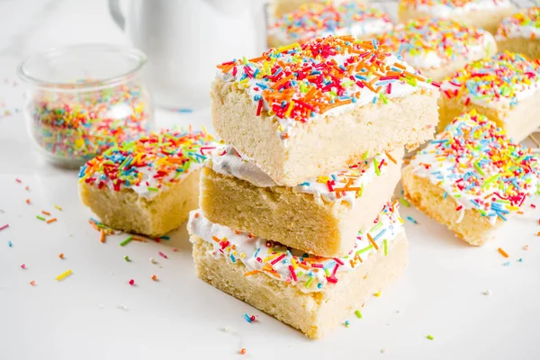 Frosted Sugar Cookie Bars, with sugar topping and colorful sugar crumbles, white marble background copy space