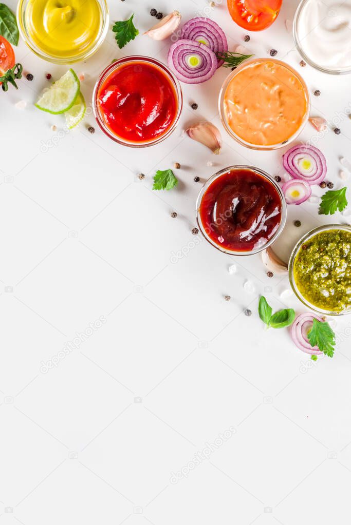 Set of sauces in small bowls - ketchup, mayonnaise, mustard, bbq sauce, pesto, classic burger sauce, with spices and herbs in. White background copy space top view
