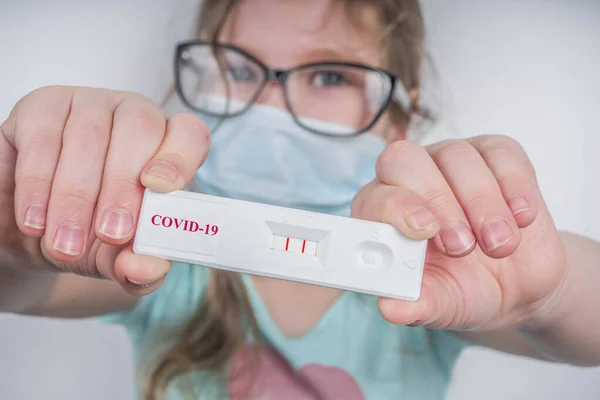 Worldwide coronavirus epidemic concept. Pandemic COVID-19, 2019-nCoV. Kid girl with positive test strip for antibody or sars-cov-2 virus disease in hands. White background