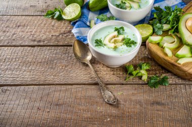 Ev yapımı avokado kremalı çorba, limon, otlar ve ahşap arka planda avokado dilimleri, kopyalama alanı