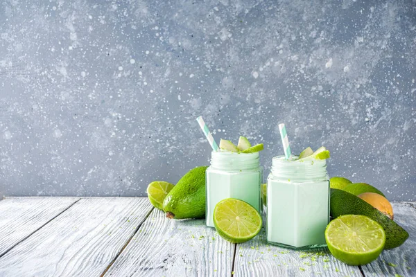 Avocado Milk Shake or Smoothie, Yogurt with Avocado and Lime Juice, with Fresh Avocados and limes on wooden background copy space