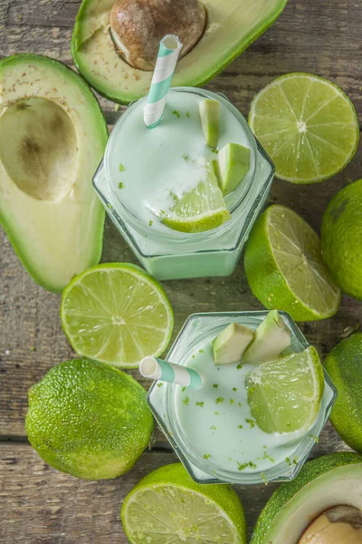 Avocado Milk Shake or Smoothie, Yogurt with Avocado and Lime Juice, with Fresh Avocados and limes on wooden background copy space