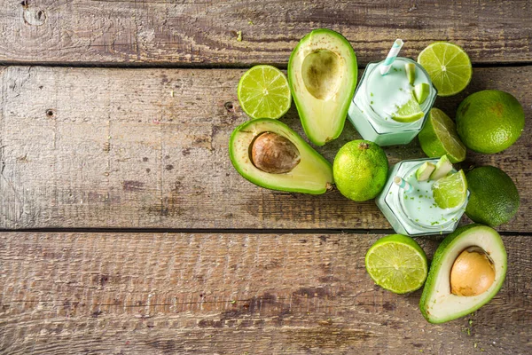 Avocado Milk Shake or Smoothie, Yogurt with Avocado and Lime Juice, with Fresh Avocados and limes on wooden background copy space