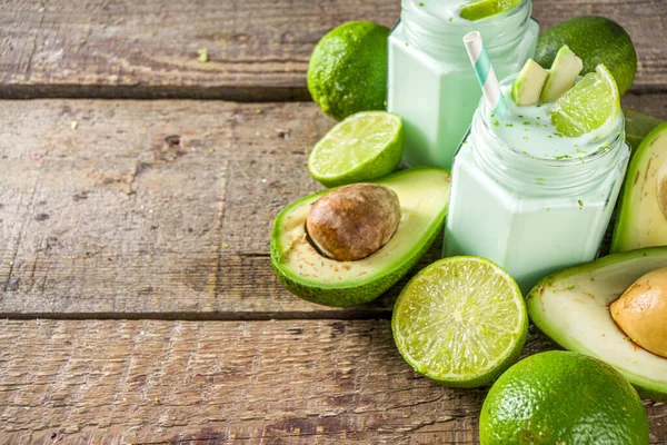 Avocado Milk Shake or Smoothie, Yogurt with Avocado and Lime Juice, with Fresh Avocados and limes on wooden background copy space