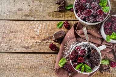 Böğürtlenli ev yapımı çikolatalı kek. Kahvaltı tarifi, sütsüz çikolatalı kek, böğürtlen, şeker tozu ve nane, ahşap kırsal arka plan.