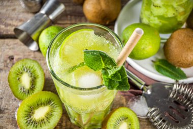 Soğuk yaz içeceği ve içecek tarifleri. Kiwi Lime Mojito kokteyli ya da limonlu alkolsüz moktail, naneli ve dilimlenmiş kivi meyveleri ahşap arka planda fotokopi alanı