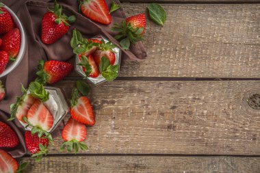 Küçük porsiyonlu kavanozlarda çilekli ve çilekli tatlı sağlıklı yoğurt, ahşap kırsal masada, kopyalama alanı.