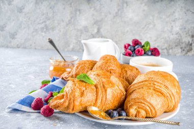 Kahve fincanı, portakal reçeli ve taze yaz meyveli tatlı tereyağlı kruvasan. Ayçöreği kavramlı geleneksel kıtasal kahvaltı, gri taş arka plan kopyalama alanı