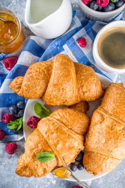 Kahve fincanı, portakal reçeli ve taze yaz meyveli tatlı tereyağlı kruvasan. Ayçöreği kavramlı geleneksel kıtasal kahvaltı, gri taş arka plan kopyalama alanı