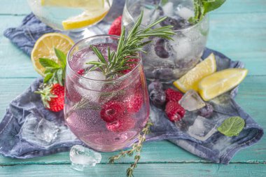 Yaz soğuk içecek konsepti. Meyve ve böğürtlen, cin tonik, limonata moktail, taze yaban mersini, ahududu, limon ve otlar, mavi yeşil ahşap arka plan fotokopi alanı
