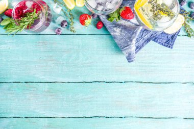 Yaz soğuk içecek konsepti. Meyve ve böğürtlen, cin tonik, limonata moktail, taze yaban mersini, ahududu, limon ve otlar, mavi yeşil ahşap arka plan fotokopi alanı