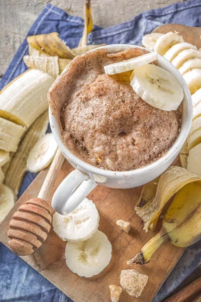 Portioned Banana bread mugcake in small mugs. Easy sweet baking idea, With fresh bananas, nuts, honey and spices on rustic wooden background copy space