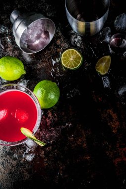 Kırmızı kozmopolit kokteyli, martini bardağında limon, koyu paslı arka plan fotokopi alanı üst görünümü.