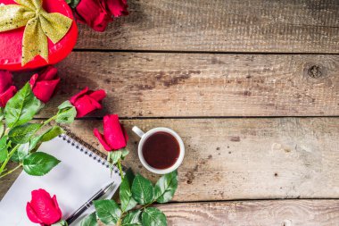 Sevgililer Günü konsepti. Tebrik kartları için arka plan. Güller, sevgililer günü hediye kutusu, bir fincan sıcak çikolata ya da kahve, not defteri. Tahta bir arkaplanda, en üst görünüm kopyalama alanı
