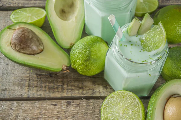 Avocado Milk Shake or Smoothie, Yogurt with Avocado and Lime Juice, with Fresh Avocados and limes on wooden background copy space