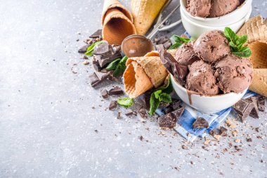 Ev yapımı çikolatalı dondurma, çikolata parçaları, talaş ve dondurma külahları. Beyaz gri taş masa üzerindeki küçük beyaz kaselerde fotokopi alanı