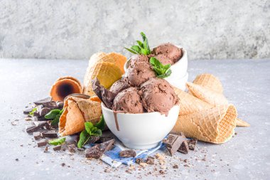 Ev yapımı çikolatalı dondurma, çikolata parçaları, talaş ve dondurma külahları. Beyaz gri taş masa üzerindeki küçük beyaz kaselerde fotokopi alanı