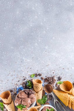 Ev yapımı çikolatalı dondurma, çikolata parçaları, talaş ve dondurma külahları. Beyaz gri taş masa üzerindeki küçük beyaz kaselerde fotokopi alanı