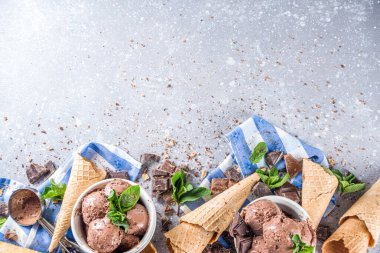 Ev yapımı çikolatalı dondurma, çikolata parçaları, talaş ve dondurma külahları. Beyaz gri taş masa üzerindeki küçük beyaz kaselerde fotokopi alanı