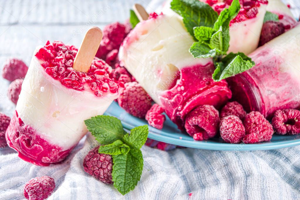 Sweet and tasty diet summer dessert. Homemade raspberry yogurt popsicle with fresh raspberries and mint. Healthy ice cream recipe. Wooden white background copy space