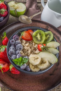 Kahvaltı yulafı. Sabah yulaf ezmesi, çeşitli meyve ve meyveler, kırsal ahşap arka plan fotokopi alanı