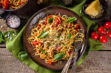 Geleneksel İtalyan makarna marinara. Klasik Roma yemeği tarifi. Ahşap arka planda fesleğen yapraklı makarna.