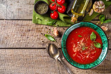 Yaz ev yapımı soğuk domates kremalı çorba. Taze gazpacho, parmesan peynirli domates püresi çorbası, sarımsak, fesleğen. Baharat ve domatesli ahşap bir arka planda.