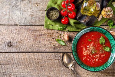 Yaz ev yapımı soğuk domates kremalı çorba. Taze gazpacho, parmesan peynirli domates püresi çorbası, sarımsak, fesleğen. Baharat ve domatesli ahşap bir arka planda.