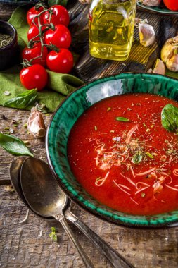 Yaz ev yapımı soğuk domates kremalı çorba. Taze gazpacho, parmesan peynirli domates püresi çorbası, sarımsak, fesleğen. Baharat ve domatesli ahşap bir arka planda.