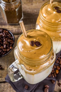 Moda içeceği, dalgona kahvesi. Kremalı kahve, soğuk süt ve şekerli. Yumuşak kremalı kahve içeceği, ahşap kırsal arka planda, kopyalama alanı