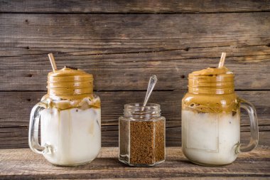 Moda içeceği, dalgona kahvesi. Kremalı kahve, soğuk süt ve şekerli. Yumuşak kremalı kahve içeceği, ahşap kırsal arka planda, kopyalama alanı