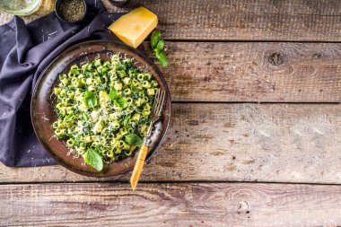Ditaloni rigati bahar tarifi, ıspanaklı yeşil ditalini makarna, yeşil pesto sosu ve peynir, kırsal ahşap arka plan.
