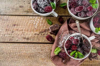 Böğürtlenli ev yapımı çikolatalı kek. Kahvaltı tarifi, sütsüz çikolatalı kek, böğürtlen, şeker tozu ve nane, ahşap kırsal arka plan.