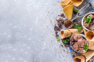 Ev yapımı çikolatalı dondurma, çikolata parçaları, talaş ve dondurma külahları. Beyaz gri taş masa üzerindeki küçük beyaz kaselerde fotokopi alanı