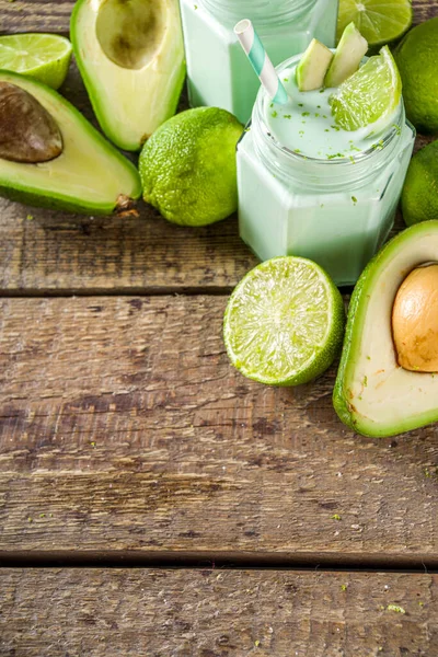 Avocado Milk Shake or Smoothie, Yogurt with Avocado and Lime Juice, with Fresh Avocados and limes on wooden background copy space