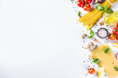 Makarna pişirmek için İtalyan yemekleri. Çeşitli malzemeli çiğ spagetti makarna - soğan, domates, sarımsak, fesleğen, maydanoz, peynir, zeytinyağı. Beyaz tablo arkaplanında, düz kopya alanı