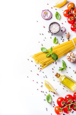 Makarna pişirmek için İtalyan yemekleri. Çeşitli malzemeli çiğ spagetti makarna - soğan, domates, sarımsak, fesleğen, maydanoz, peynir, zeytinyağı. Beyaz tablo arkaplanında, düz kopya alanı