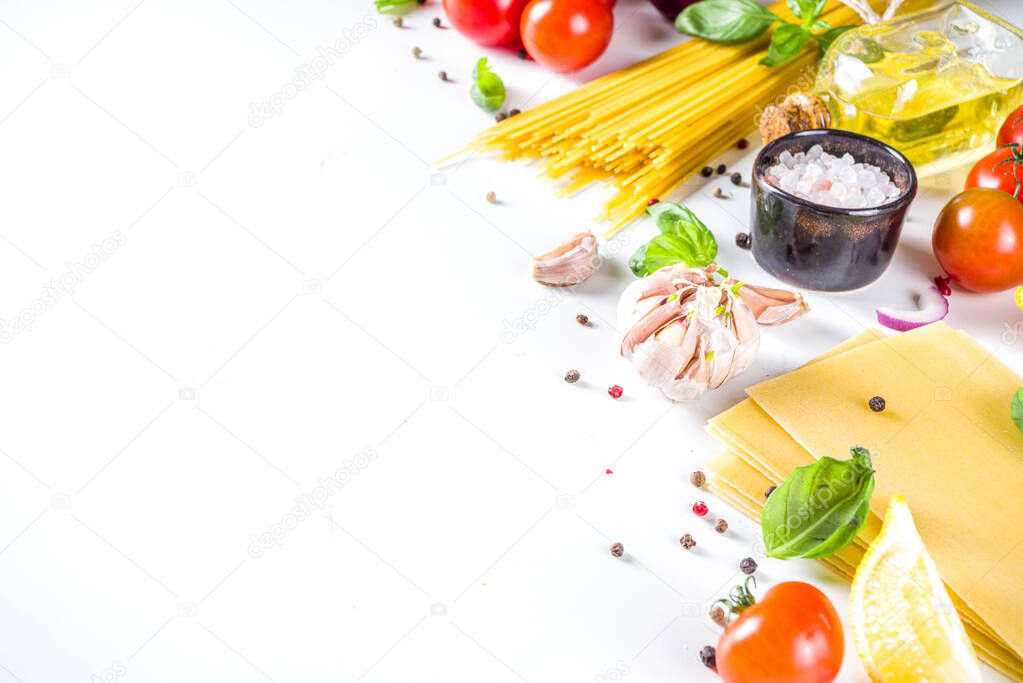 Italian food ingredients for  cooking Spaghetti Pasta. Raw spaghetti pasta with various ingredient - onion, tomatoes, garlic, basil, parsley, cheese, olive oil. On white table background, flatlay copy space