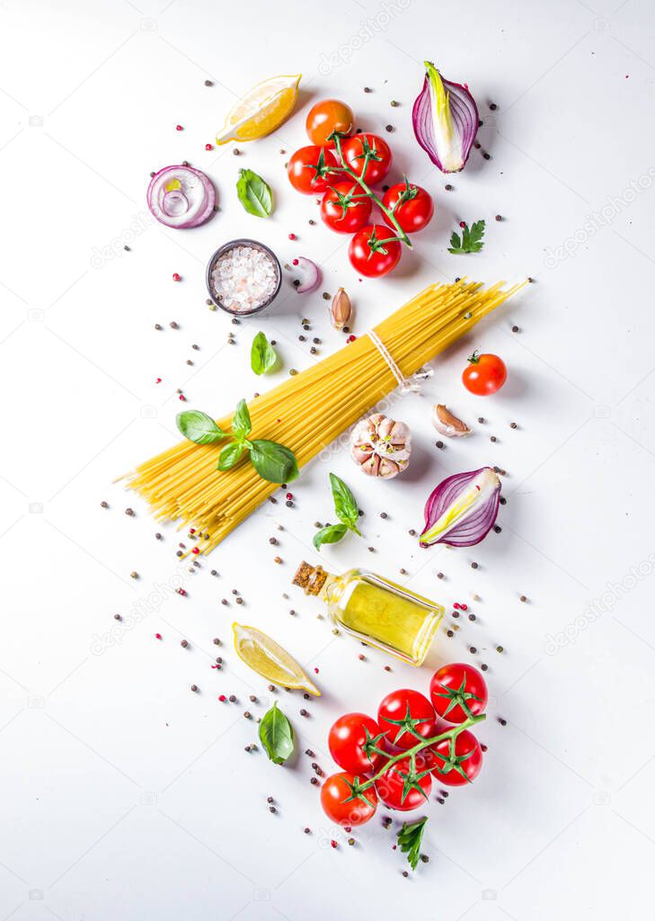 Italian food ingredients for  cooking Spaghetti Pasta. Raw spaghetti pasta with various ingredient - onion, tomatoes, garlic, basil, parsley, cheese, olive oil. On white table background, flatlay copy space