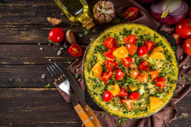 Ev yapımı rustik frittata. Tavada ıspanaklı, peynirli ve domatesli frittata. Sebzeli ahşap arkaplan Kopya alanı