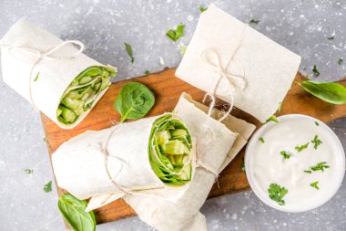 Vejetaryen taze tortilla sebzeyle sarılır. Taze pita ruloları, tofu, salatalık, bebek ıspanağı ve avokado. Gri beton arka plan kopyalama alanı