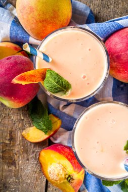 Yaz kahvaltısı içeceği, taze şeftalili smoothie, şeftalili yoğurt nektarin dilimleri, kırsal ahşap arka plan fotokopi alanı.