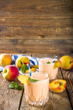 Yaz kahvaltısı içeceği, taze şeftalili smoothie, şeftalili yoğurt nektarin dilimleri, kırsal ahşap arka plan fotokopi alanı.