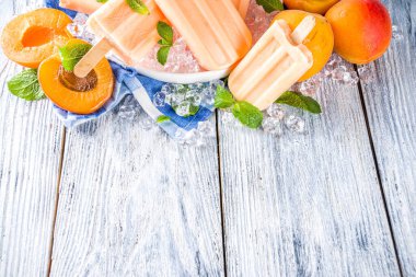 Ev yapımı kayısılı dondurma, meyveli lolipop sütsüz vejetaryen kayısı dondurması, gri eski ahşap arka plan fotokopi alanı üst görünümü.